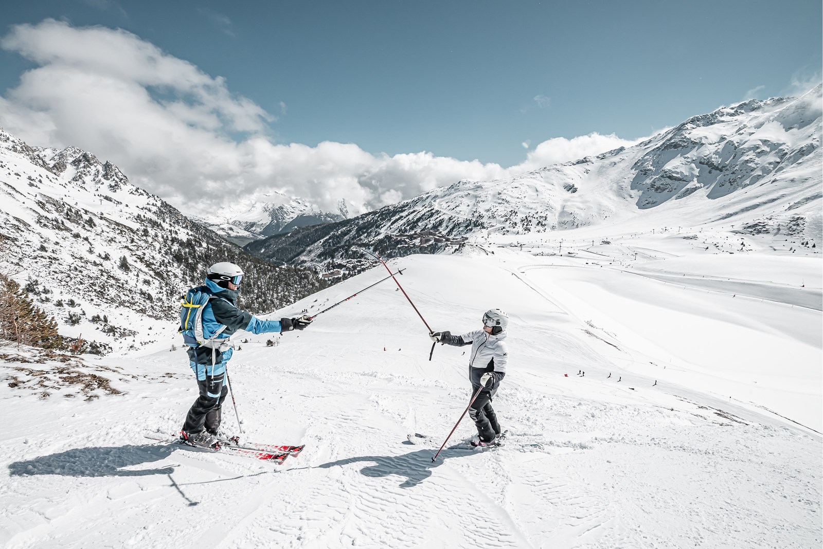 Un femme et un homme font un check de batons de ski sur une piste enneigée des Arcs 1950